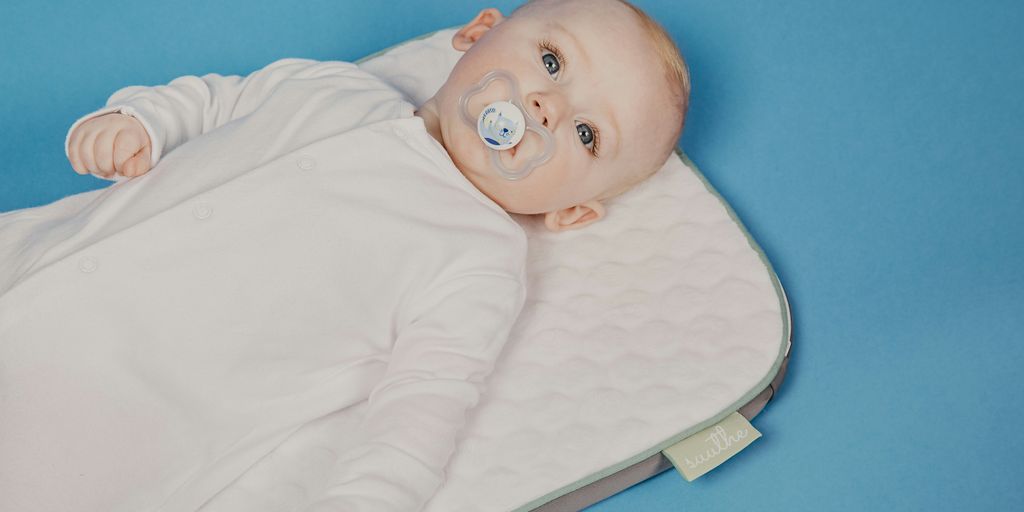 baby in white onesie lying on bed