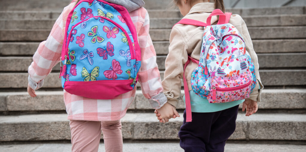 Mochila e Lancheira Infantil: O Kit Perfeito para o Volta às Aulas 1 duas meninas com lindas mochilas nas costas vao para escola juntas conceito de amizade de infancia