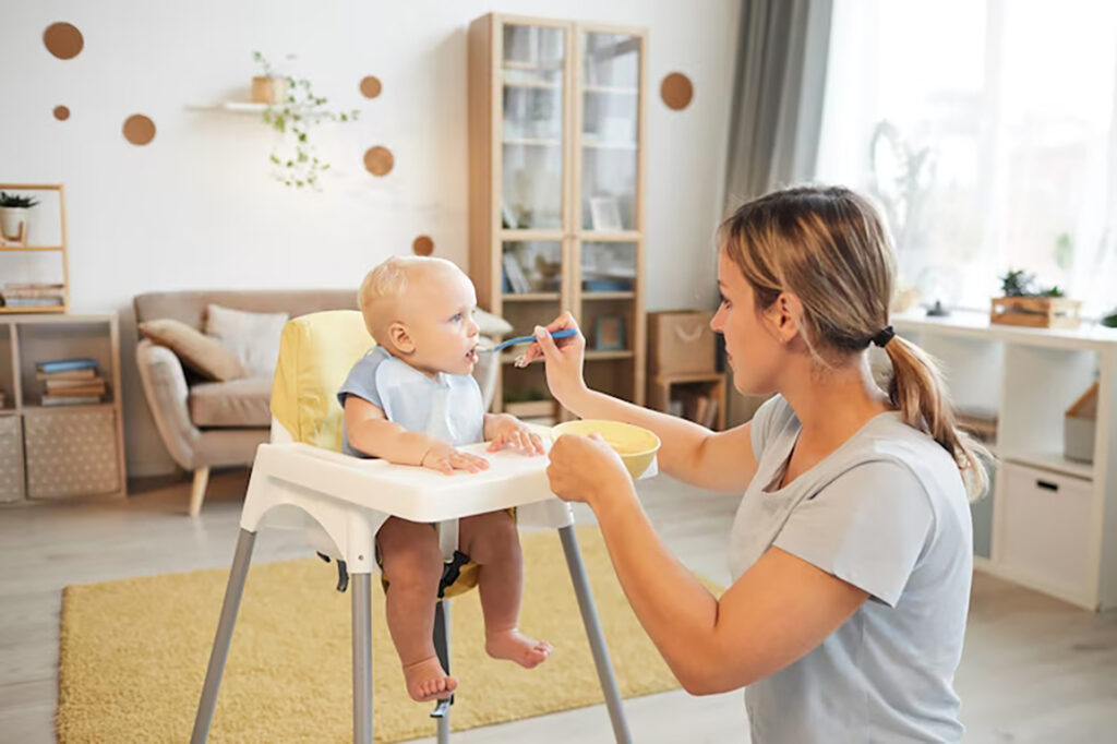 mulher adulta moderna alimentando seu filho bebe alegre com mingau na sala de estar em casa 236854 2