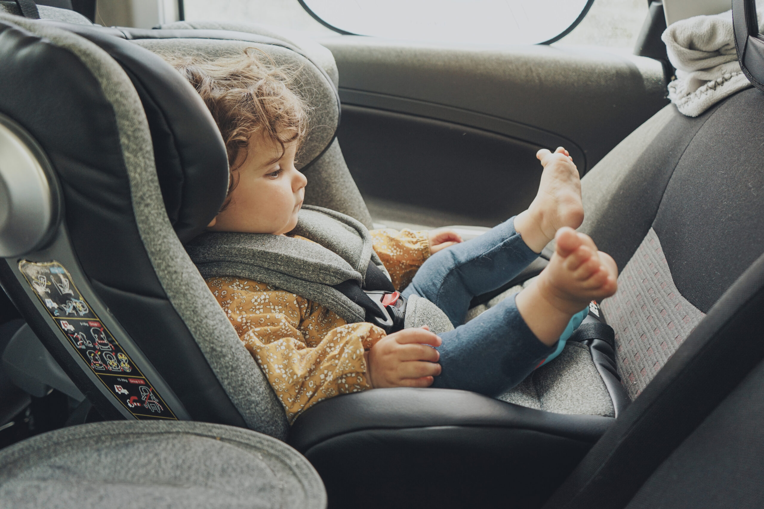 Toddler inside a car sit in her baby safety seat